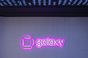 Galaxy logo sign illuminated by neon pink light glowing beneath the sign.